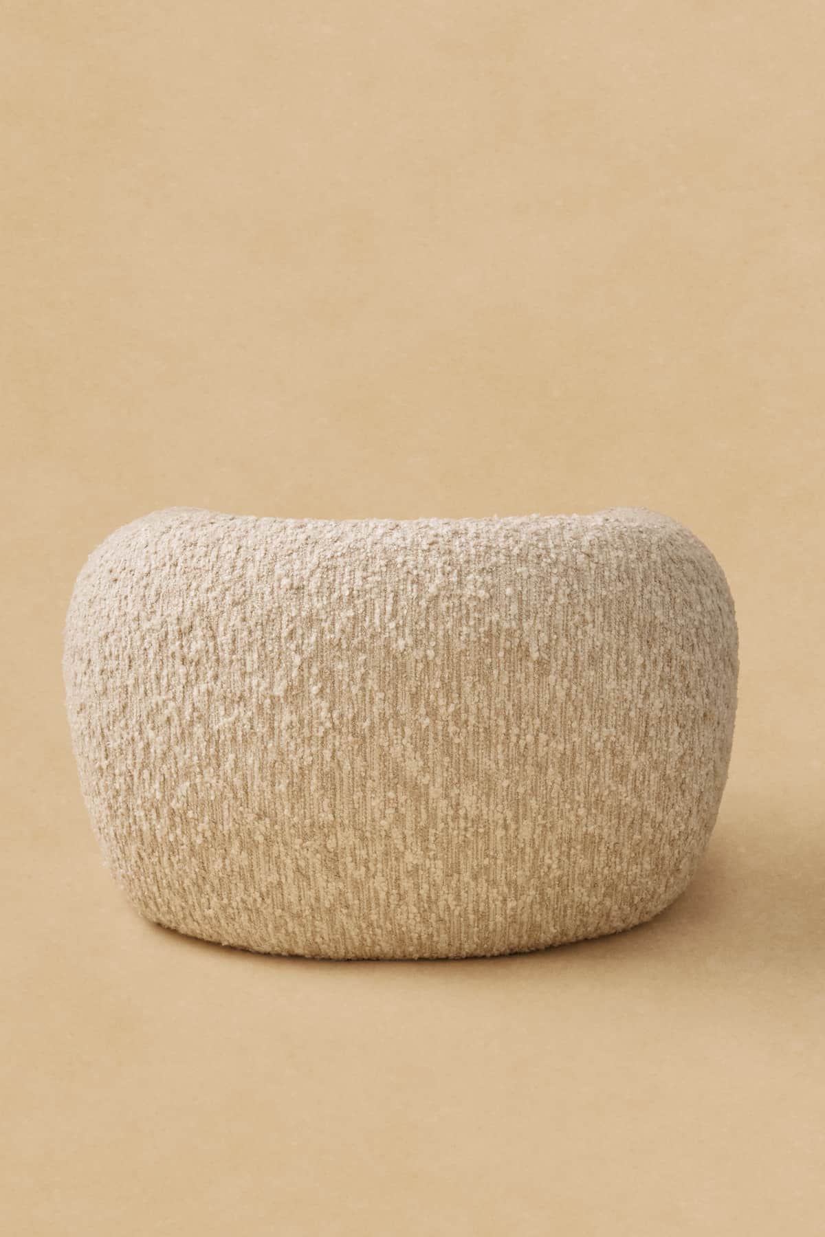 A light beige, rectangular ottoman with rounded edges, upholstered in a textured boucle fabric, appe… — 3D model