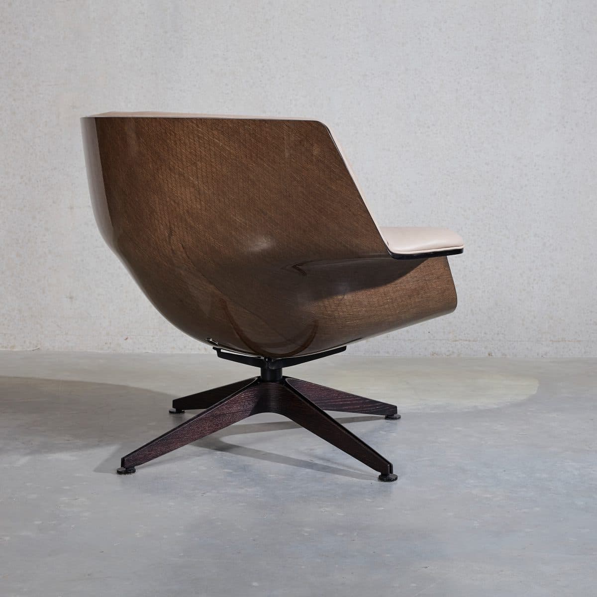 A modern lounge chair featuring a continuous, curved shell made from dark-stained molded plywood. The chair incorporates light-colored upholstered pads for the seat and lower back. It is supported by a dark-finished, four-star swivel base with splayed legs. — 3D model