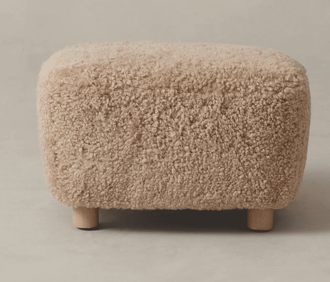 A rectangular ottoman or footrest upholstered in a light beige, fluffy, boucle-textured fabric, supported by four short, light-colored wooden cylindrical legs. — 3D model