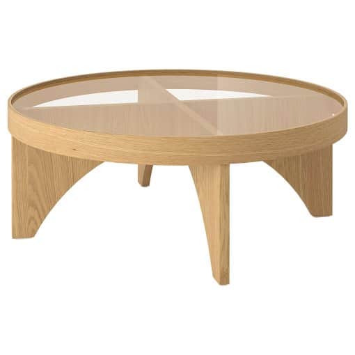 A circular coffee table featuring a light-toned wooden frame and a clear glass top. Beneath the glas… — 3D model