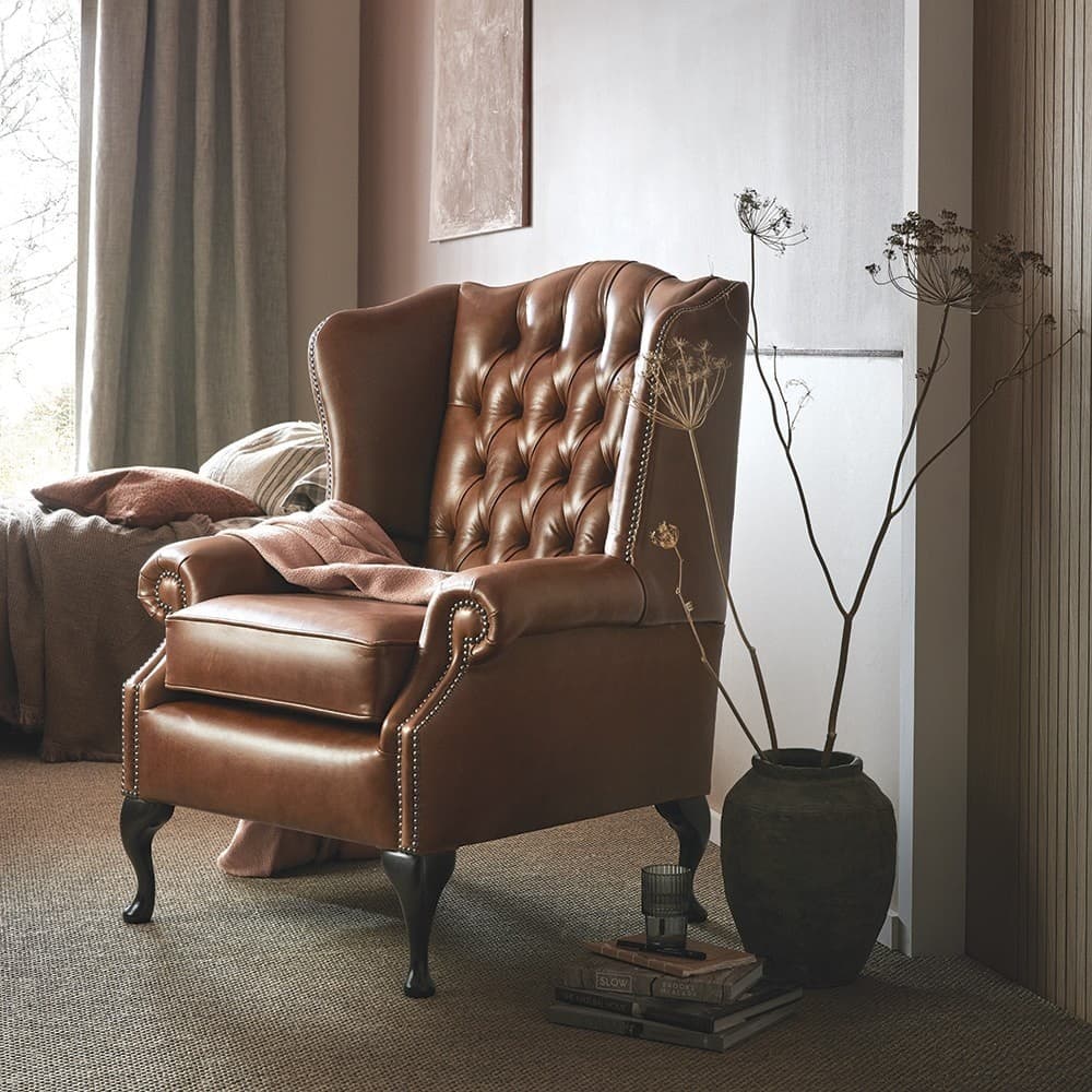 A classic wingback armchair upholstered in rich brown leather, featuring deep button tufting on the backrest, decorative nailhead trim along the armrests and base, and elegant dark wood cabriole legs. It has a plush seat cushion and rolled arms. — 3D model