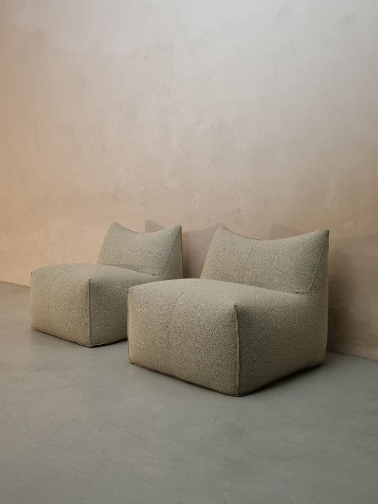 An armless, upholstered lounge chair with a low profile and a subtly curved backrest, covered in textured beige fabric. — 3D model