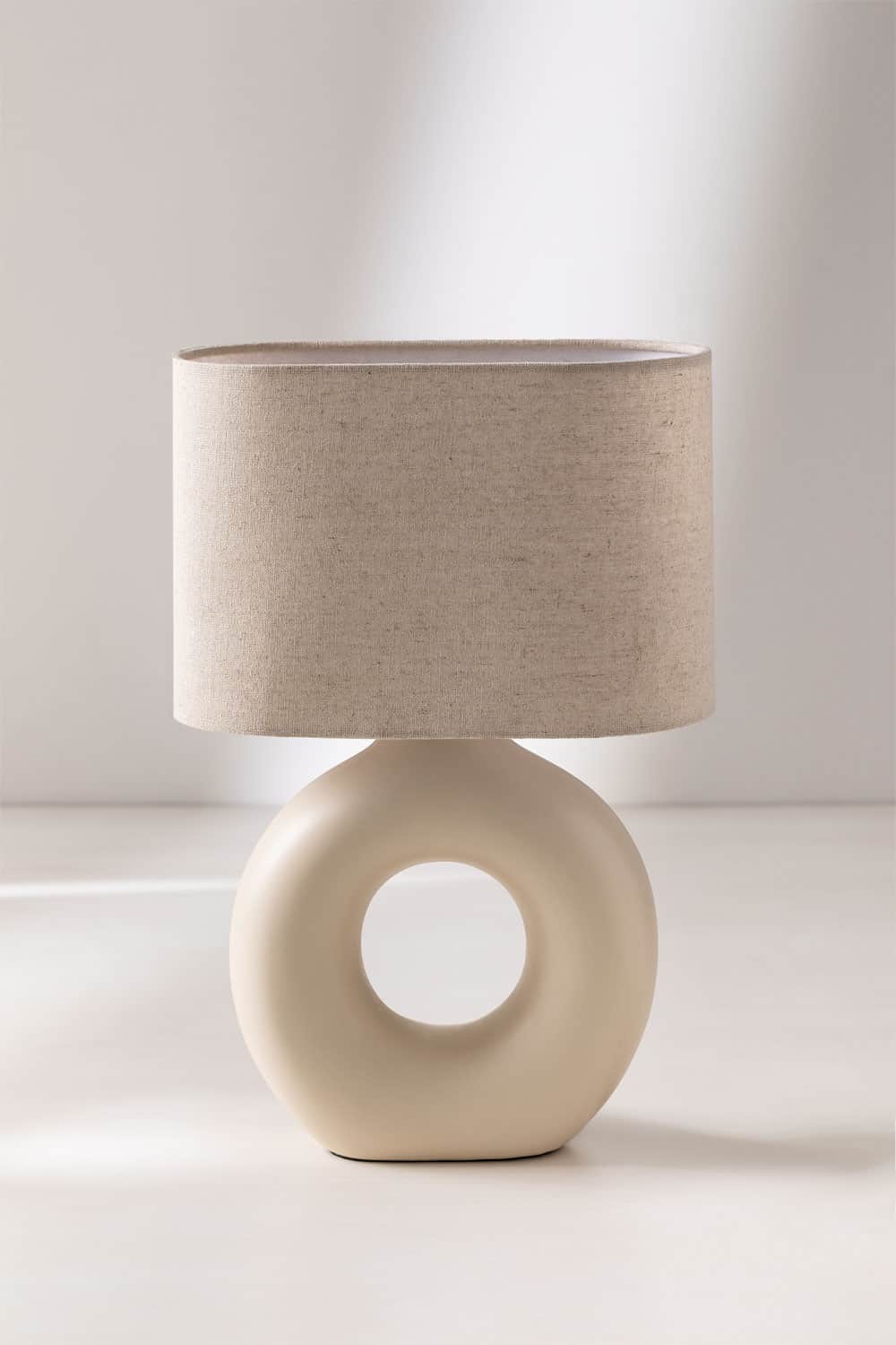 A modern table lamp featuring a cream-colored ceramic torus-shaped base with a central cut-out, topp… — 3D model