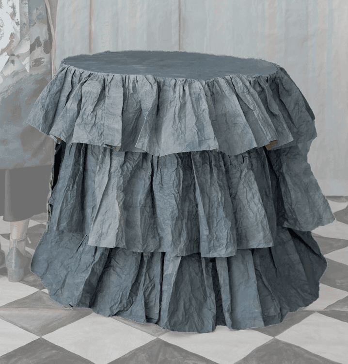 A cylindrical accent table entirely covered in multiple tiers of ruffled, crumpled blue-grey fabric,… — 3D model