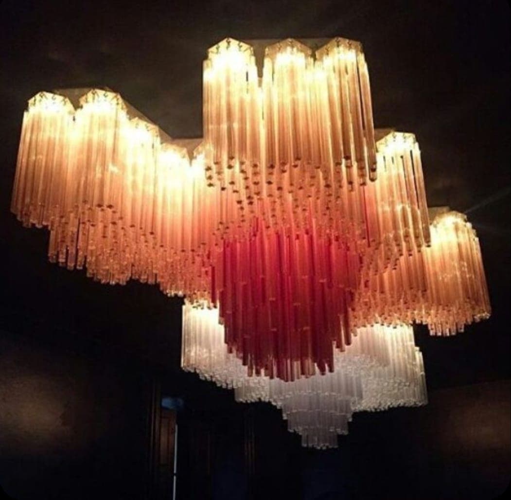 A large, multi-tiered chandelier featuring an ombré color gradient from deep red at the center to clear/light peach at the outer edges, composed of numerous vertical glass tubes. — 3D model
