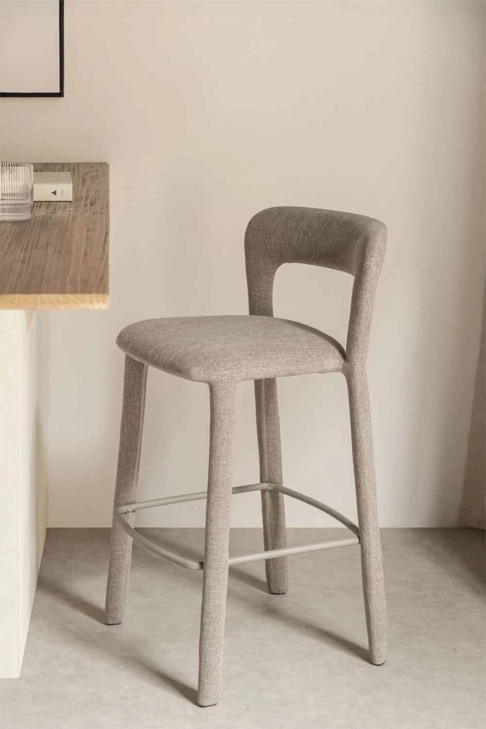 A modern bar stool with a slightly curved backrest and a seat upholstered in a textured beige fabric… — 3D model