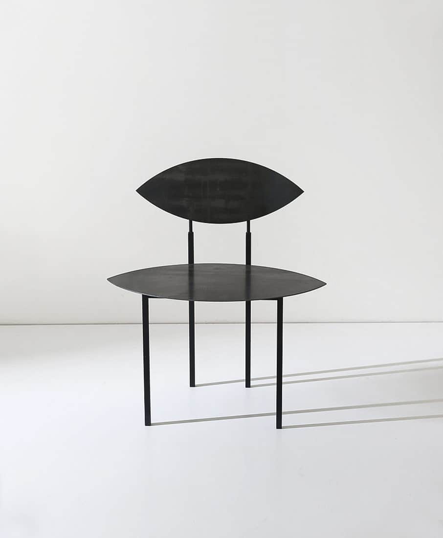 A minimalist black metal chair featuring a sculptural design with lenticular, eye-shaped seat and ba… — 3D model