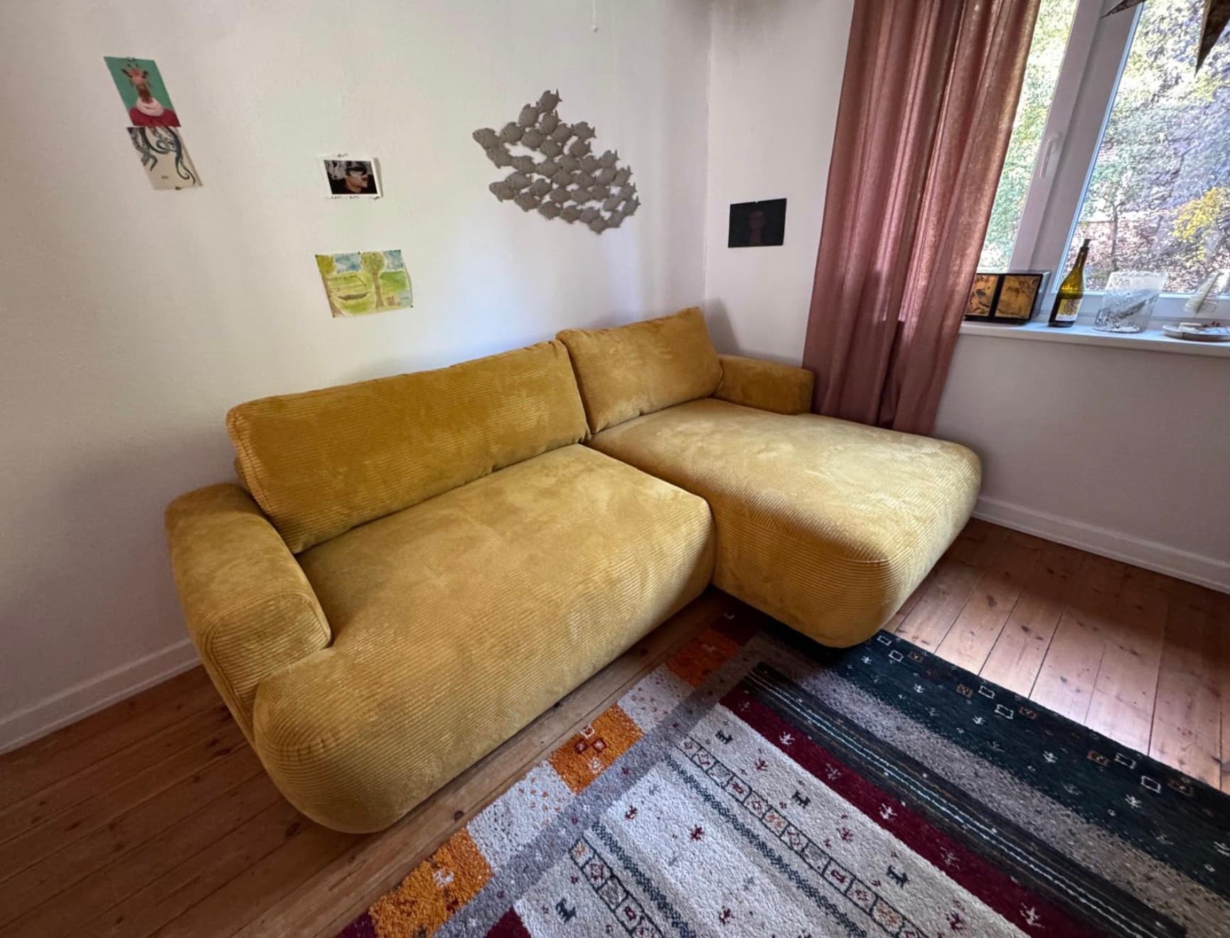 A contemporary modular sectional sofa featuring a chaise lounge component, upholstered in a distinct ribbed mustard yellow fabric. The design emphasizes comfort with thick, plush cushions and rounded edges throughout its form, including the armrests and base. — 3D model