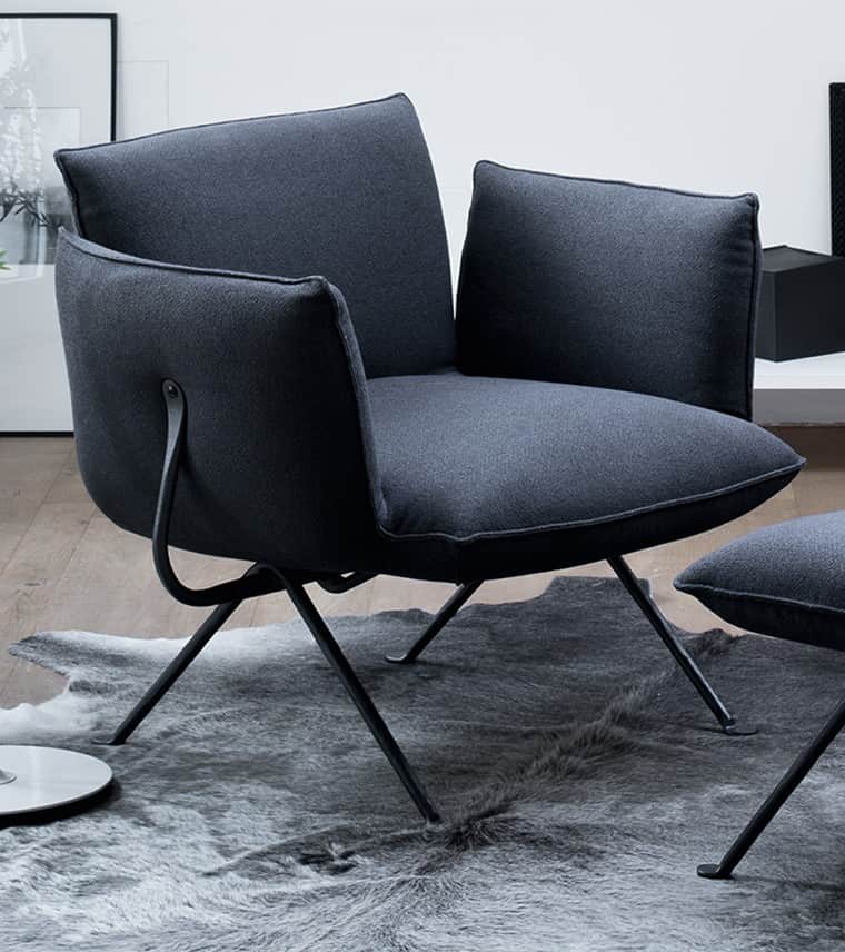 A modern dark gray upholstered lounge chair with a minimalist black metal frame. It features plush,… — 3D model