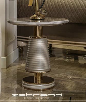 A modern accent table featuring a round white marble top with grey veining, a central inverted conical pedestal base with horizontal white ribbing, and polished gold metallic accents on the top, middle, and tiered circular bottom base. — 3D model