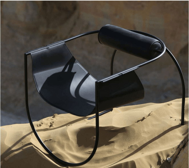 A contemporary black chair with a minimalist design. It features a curved, seat-like structure made of flat metal, supported by thin, black metal tubing that forms the legs and frame. A cylindrical element, possibly a backrest or armrest, is integrated into the upper part of the frame. — 3D model