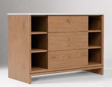 A modern dresser with a light wood finish and a white top surface. It features three drawers with brass knob hardware, flanked by open shelving units on either side. The dresser has a clean, minimalist design with visible wood grain. — 3D model