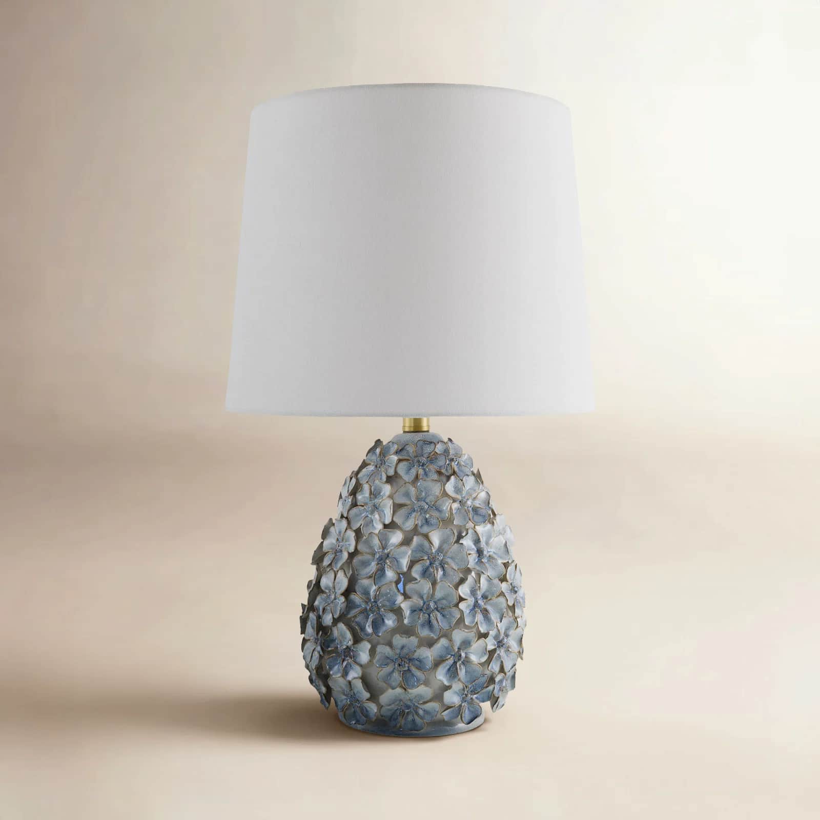 A decorative table lamp featuring a white tapered drum shade and an ornate ceramic base adorned with… — free OBJ 3D model
