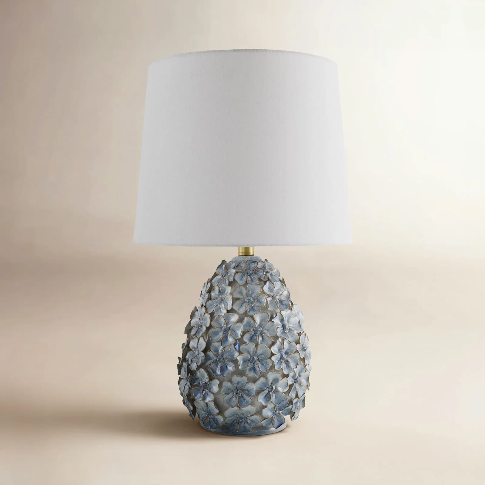 A decorative table lamp featuring a white tapered drum shade and an ornate ceramic base adorned with numerous three-dimensional light blue flowers. — 3D model
