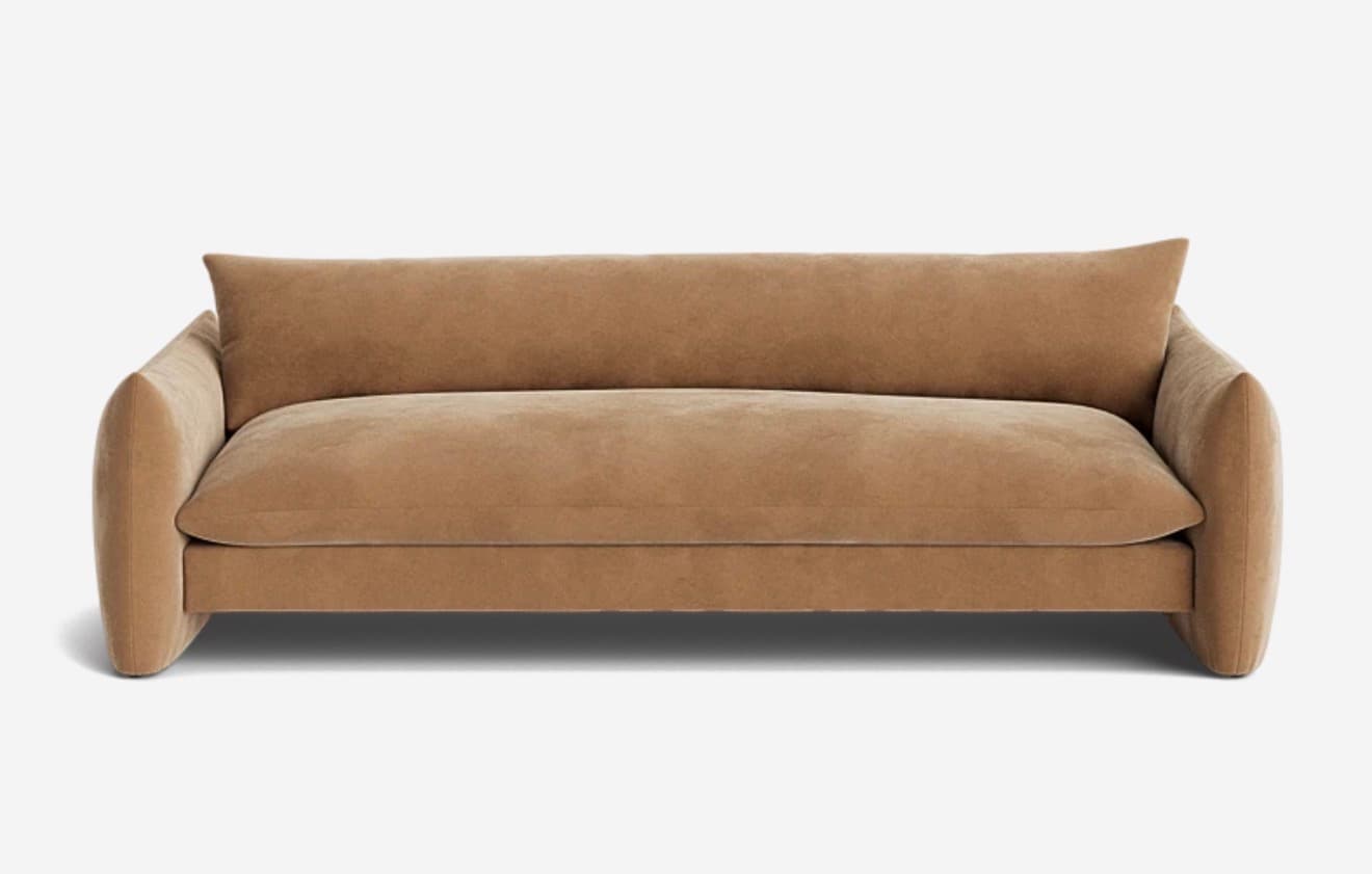 A contemporary, plush sofa with a low profile and rounded arms. The sofa features a single, deep seat cushion and a continuous back cushion that curves slightly at the ends. The upholstery appears to be a soft, textured fabric. The overall design is minimalist and inviting, with a focus on comfort. — 3D model