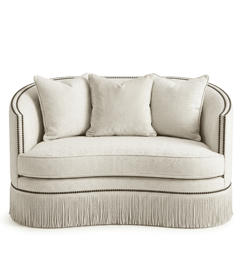 An elegant curved loveseat featuring textured off-white upholstery, detailed with black nailhead trim along its top edge and arms. The base is adorned with a decorative fringe skirt. It includes two matching throw pillows. — 3D model