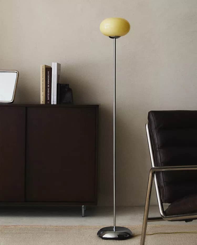 A modern floor lamp with a slender, polished metal stem rising from a circular, reflective base. Top… — 3D model