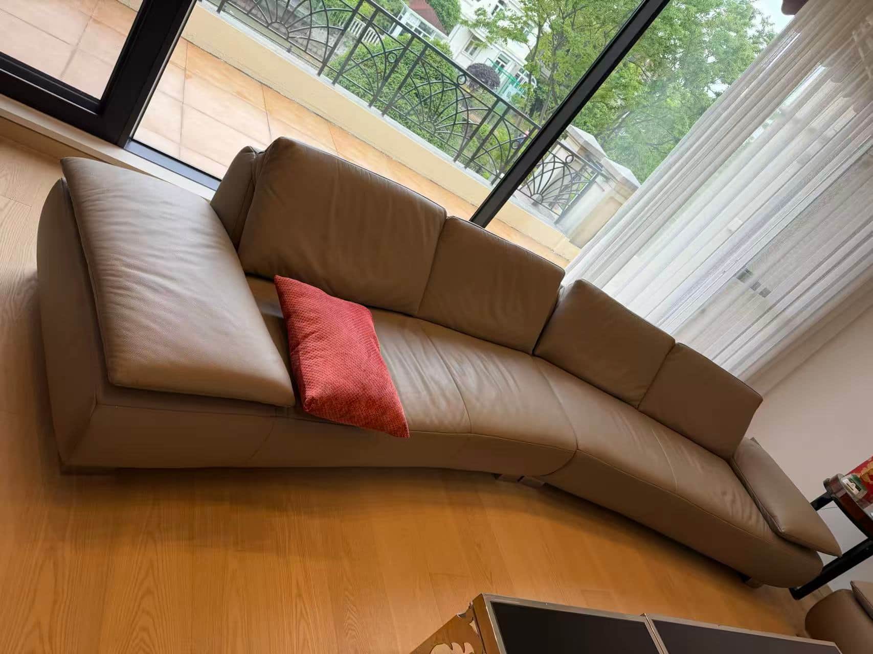 A modern curved sectional sofa upholstered in beige leather, featuring a low profile design and poli… — 3D model