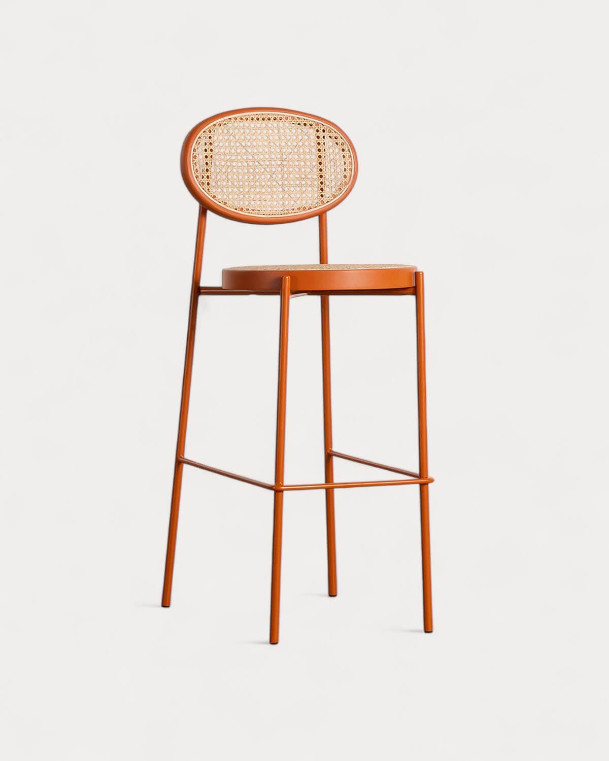 A modern bar stool featuring a slender burnt orange metal frame, an oval backrest with natural cane webbing, and a circular seat also with matching cane. It includes an integrated footrest for comfort. — 3D model