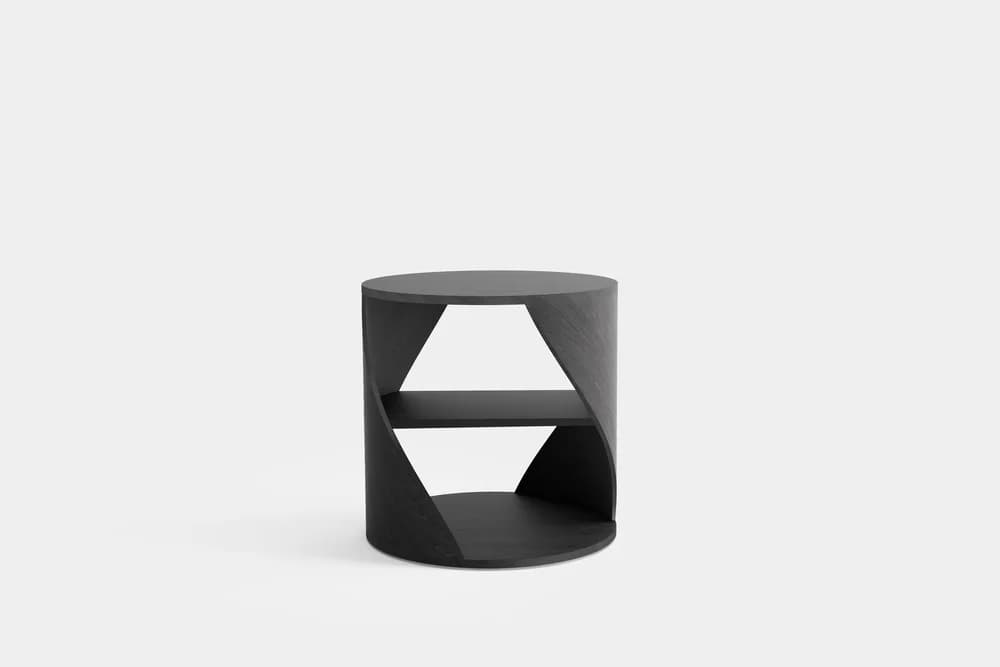 A cylindrical side table with an open, abstract design. It features a circular top and base. The main body has a curved vertical element that is intersected by a horizontal shelf. The sides have geometric cutouts, creating a sense of depth and visual interest. The overall form suggests a modern or contemporary aesthetic. — 3D model