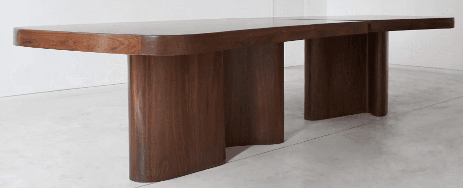 A modern dining table with a rich walnut finish, featuring a rectangular top with softly rounded corners. The table is supported by two distinct, wavy, sculptural pedestal bases, offering a unique and stable foundation. — 3D model