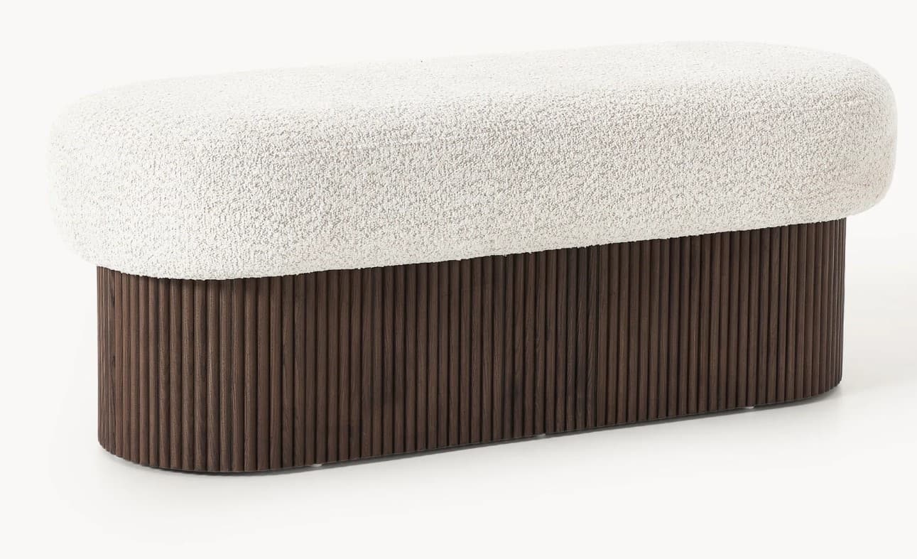 An elongated, oval-shaped bench featuring a plush, textured cream boucle upholstered top set upon a solid, dark brown wood base with vertical reeding details. The design is contemporary, emphasizing both tactile comfort and a structured, organic aesthetic. — 3D model