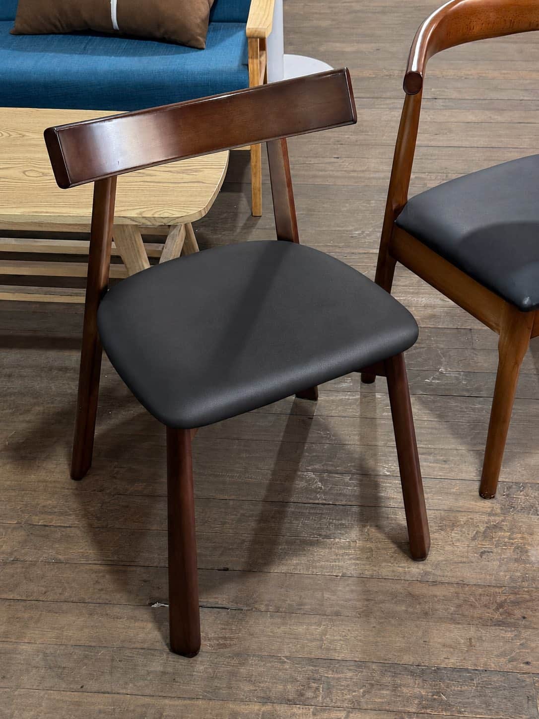 An armless modern dining chair featuring a dark brown wooden frame and a black upholstered seat. The… — 3D model