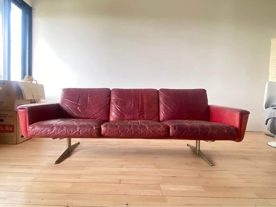 A three-seater sofa with a low profile and square arms. The sofa is upholstered in a red, textured m… — free GLTF 3D model