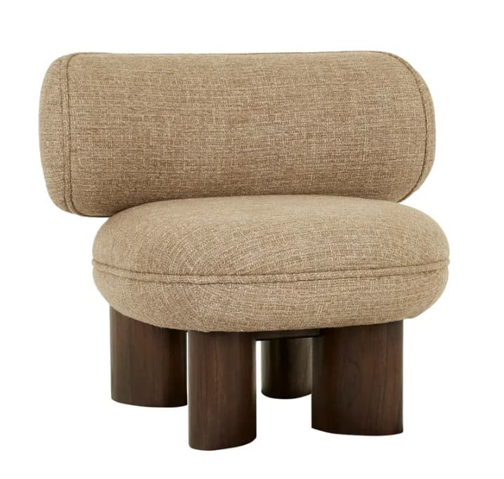 A contemporary accent chair with a distinctive, plush design. The chair features a rounded seat and a cylindrical, slightly curved backrest, both upholstered in a textured, neutral-toned fabric. It is supported by four dark, cylindrical legs that are spaced unevenly, adding to its unique aesthetic. The upholstery exhibits subtle stitching details that enhance its form. — 3D model
