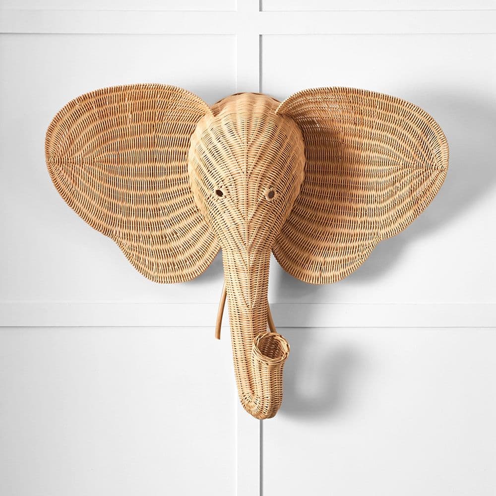 A natural-toned decorative wall sculpture in the shape of an elephant's head, intricately woven from wicker or rattan. The piece features large, flared ears and a distinctive, curled trunk, all crafted with visible woven texture, suggesting it is designed for wall mounting as a decorative accent. — 3D model