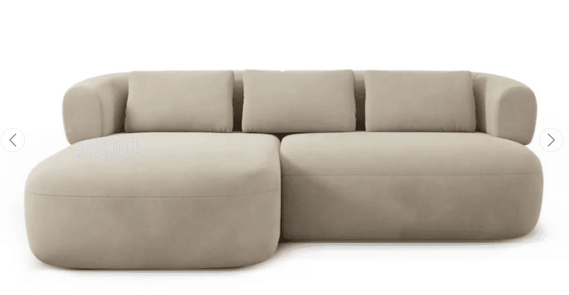 A contemporary sectional sofa featuring a left-hand facing chaise lounge and a two-seat sofa component. The piece is upholstered in a soft, neutral-toned fabric, possibly velvet or boucle, in a light beige or cream color. Its design is characterized by generous, rounded forms, thick integrated armrests, and plush back cushions, all contributing to a modern and inviting aesthetic. — 3D model