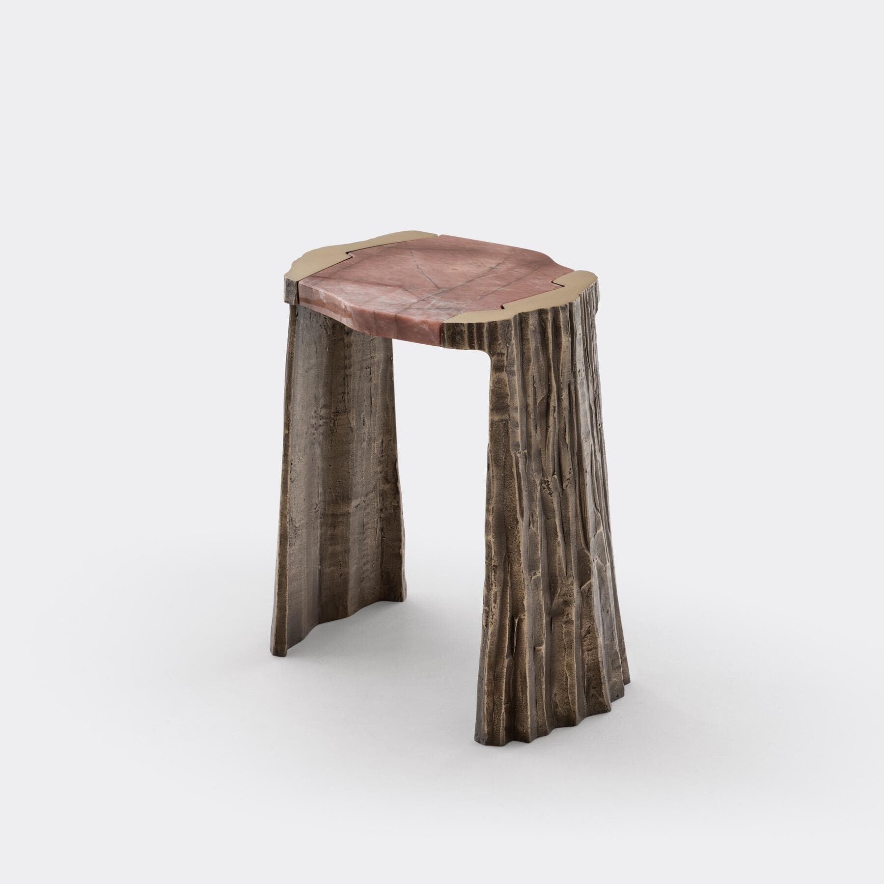 A sculptural accent table featuring an irregular reddish natural stone top, bordered by a thin brass trim. The base is composed of three sturdy legs crafted from what appears to be cast bronze, exhibiting a heavily textured, bark-like finish in a dark, weathered tone. The overall design emphasizes organic forms and robust materials. — 3D model