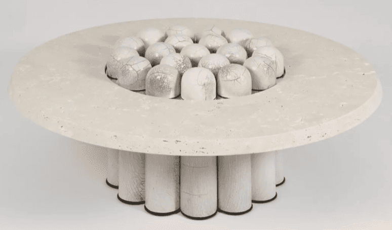 A circular coffee table with a travertine-like top featuring a central decorative element composed o… — 3D model