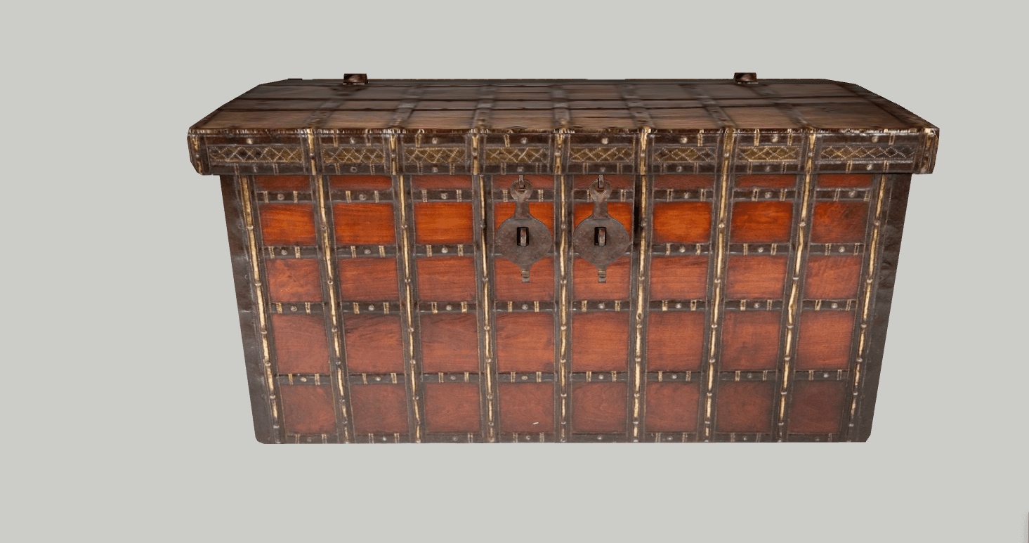 A robust, rectangular wooden storage chest, heavily adorned and reinforced with metal. The chest features a dark-stained wood body with numerous vertical and horizontal brass strips secured by visible rivets. The top edge includes intricate brass patterned inlay. Two prominent, ornate iron latches are positioned centrally on the front, providing a secure closure. The overall aesthetic is traditional and sturdy, indicative of antique craftsmanship. — 3D model