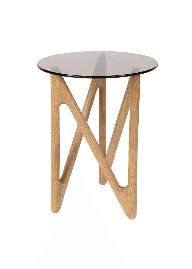 A contemporary accent table featuring a round, clear glass top supported by a unique light oak wood base. The base consists of interlocking, angular wooden elements forming a striking geometric pattern with cut-outs, providing stability and a distinctive aesthetic. — 3D model