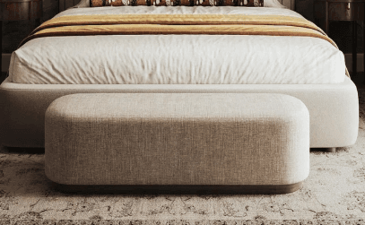 A rectangular ottoman with rounded corners, upholstered in a textured, light-colored fabric. It features a dark, possibly wood, base that slightly recesses from the upholstered body. — 3D model