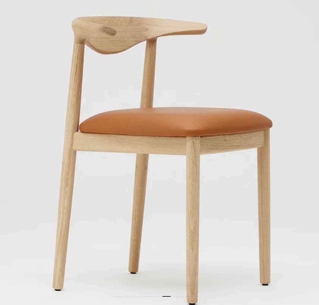 A modern dining chair crafted from light oak wood, featuring a distinctive curved wooden backrest and a padded, caramel-colored leather upholstered seat. The chair has a minimalist design with four straight, tapered round legs. — 3D model