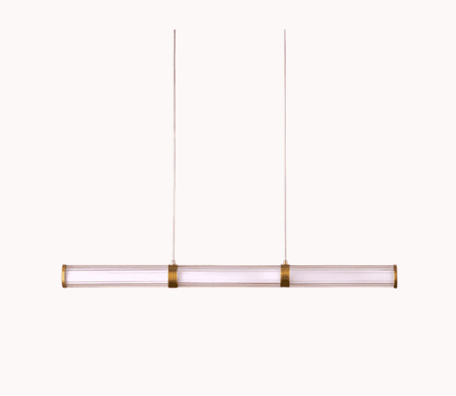 A modern linear pendant light featuring a clear glass or acrylic cylindrical shade housing an internal LED light source. It is suspended by two thin wires and accented with brass-colored metal bands at either end and in the center. — 3D model