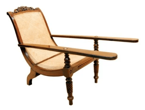 A traditional colonial-style lounge chair featuring a sturdy dark wood frame and woven cane for both the seat and backrest. The back is gently reclined, and the frame exhibits decorative carved elements on the crest rail and turned, reeded details on the front legs and armrest supports. The armrests are long and flat, providing ample support. — 3D model