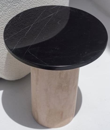 A contemporary round pedestal table featuring a polished black marble top with white veining, supported by a thick cylindrical base with a textured, light beige finish, likely plaster or concrete. — 3D model