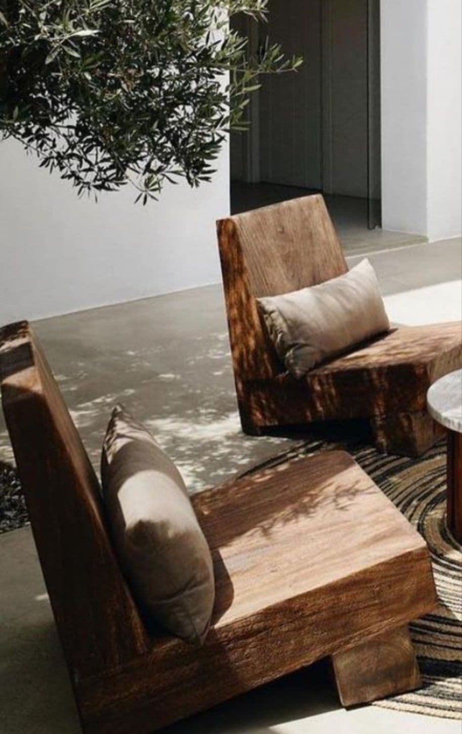 A modern armchair with a solid, blocky construction. It features a low profile with a thick seat and a reclined backrest. A rectangular lumbar pillow is placed against the backrest. The overall design is minimalist and appears to be crafted from solid wood. — 3D model