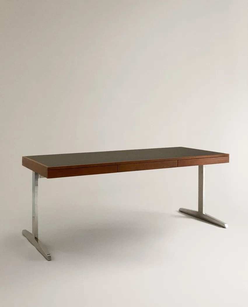 A sophisticated Mid-Century Modern executive desk featuring a rectangular wooden top with a dark inset surface, likely leather or laminate. It includes two integrated drawers and is supported by two polished metal, inverted T-shaped legs, embodying a minimalist design. — 3D model