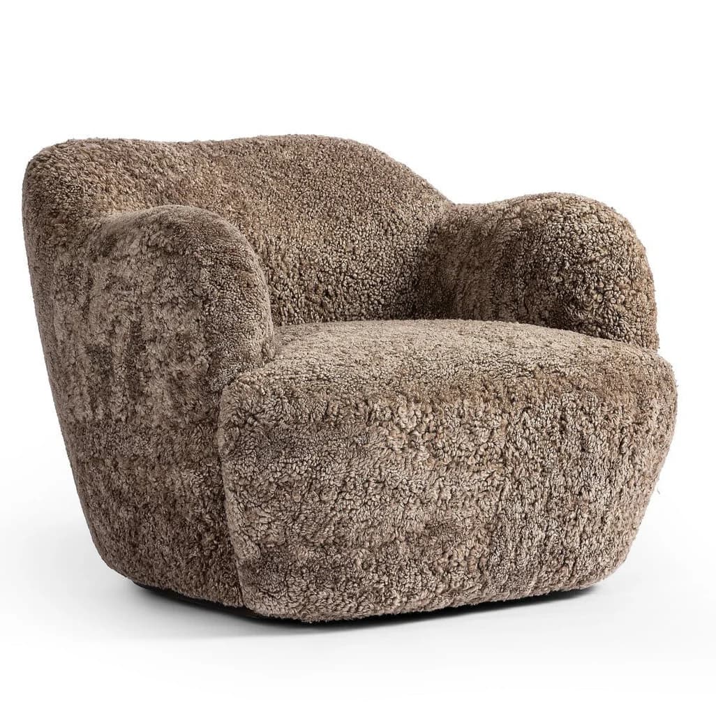 A plush, upholstered armchair with a rounded, organic silhouette. The piece features a thick, textured covering resembling sheepskin or a similar natural fiber, providing a soft and inviting appearance. The armrests are integrated into the body of the chair, flowing seamlessly into the back and seat. The base is low and broad, contributing to its sturdy and comfortable design. — 3D model