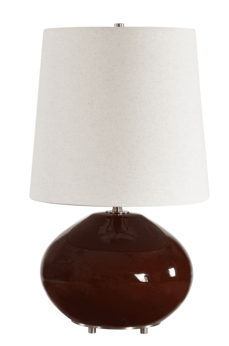 A modern table lamp featuring a bulbous, gourd-shaped ceramic base with a high-gloss dark brown glaze. It is topped with a tapered drum shade made of off-white, textured fabric. The lamp includes gold-toned metal accents visible at the base feet, the neck connecting to the shade, and as a finial. — 3D model
