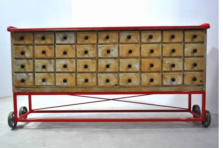 A long, rectangular storage cabinet featuring numerous small drawers, supported by a red metal frame… — 3D model