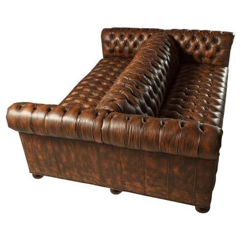 A Chesterfield-style sofa with deep button tufting across the back, sides, and seat. It features rolled arms and a low profile. A large, elongated bolster pillow with similar tufting is positioned centrally on the sofa's seating area. — 3D model