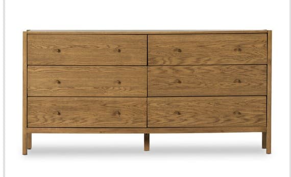 A rectangular dresser constructed from light-toned wood with a prominent natural grain. It features six drawers, arranged in two columns of three, each equipped with small, circular wooden knob pulls. The drawer fronts are flush with the frame, contributing to its minimalist aesthetic. The dresser stands on four short, straight block legs that are integrated into the base. — 3D model
