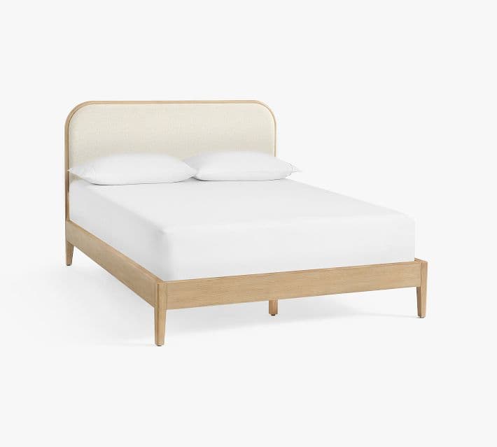 A contemporary bed frame constructed from light-toned wood, featuring a curved, upholstered headboard in a cream fabric. The frame includes side rails and subtly tapered legs. — 3D model
