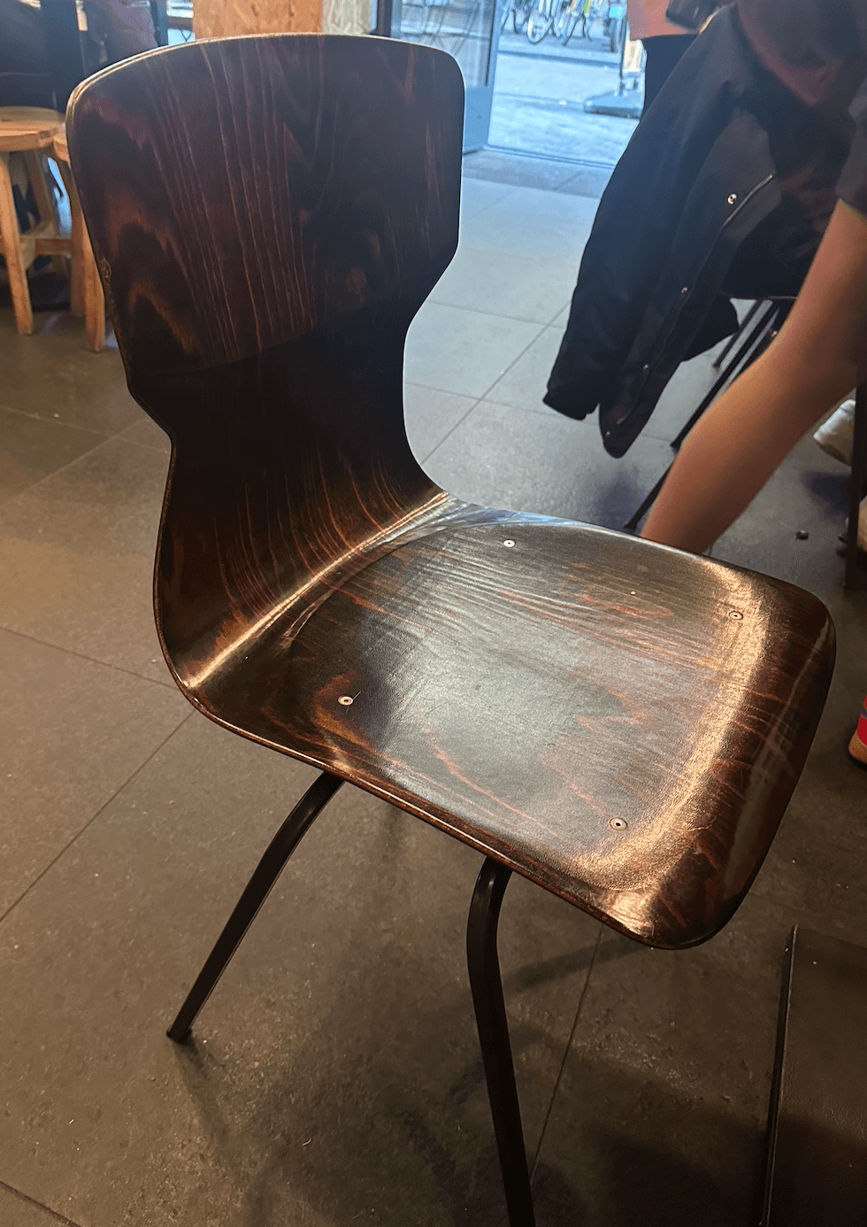 A modern side chair featuring a curved, dark wood grain molded plywood seat and back, supported by four splayed black metal legs. — 3D model