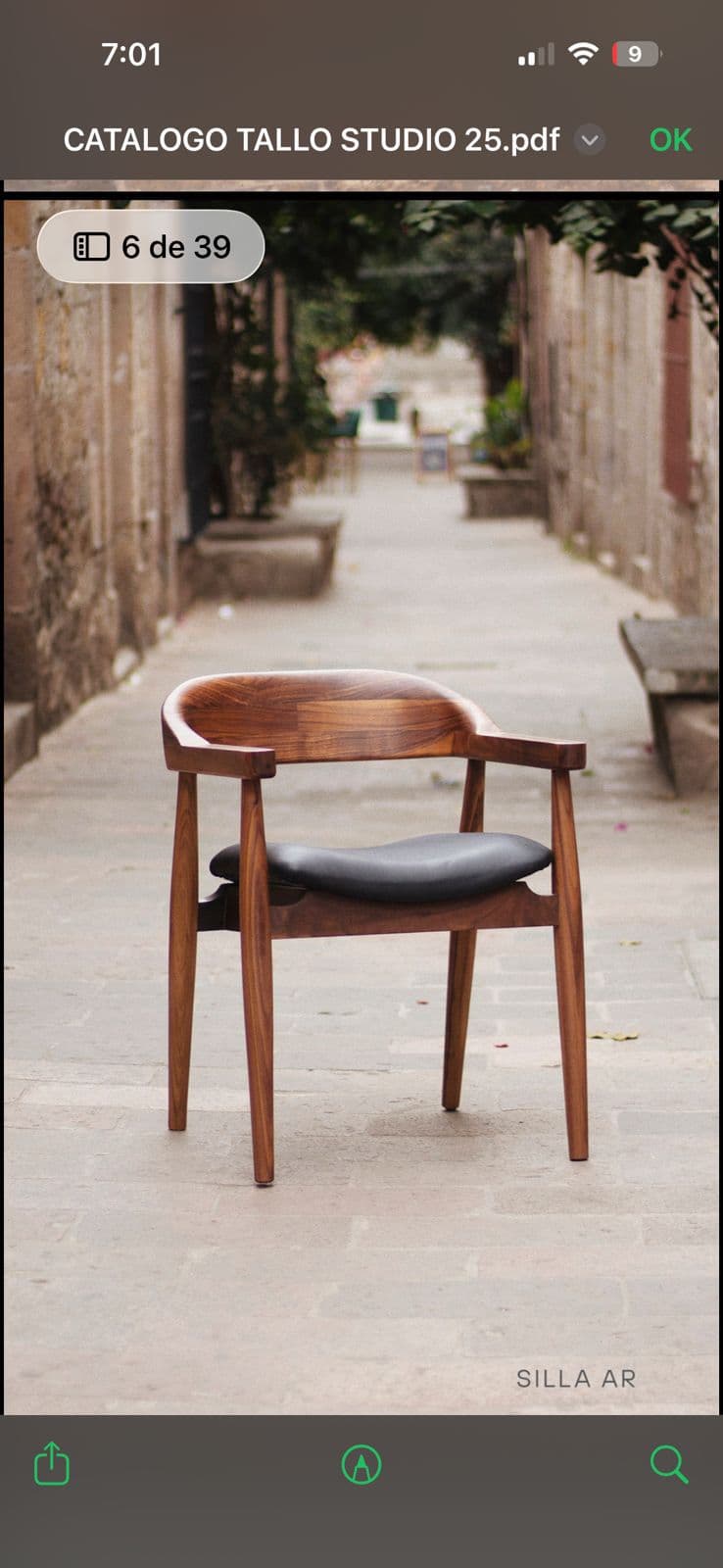 A modern armchair with a curved wooden frame and a dark upholstered seat. The chair has a solid wood construction with a visible wood grain. The backrest is integrated into the frame, forming a continuous curve. The legs are tapered, and the armrests are extensions of the back frame. — 3D model